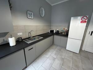 a kitchen with a white refrigerator and a tile floor at Noclegi Comfort - Self Check-in 24h in Świdnica