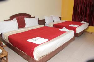 2 łóżka w pokoju hotelowym z czerwoną pościelą w obiekcie RPM Residency w mieście Kodaikānāl