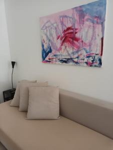 un dipinto appeso sopra un letto con cuscini di B&B Lido Apartament 10A a Civitanova Marche