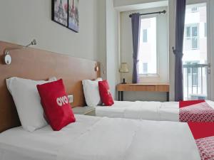 2 letti in camera con cuscini rossi e bianchi di OYO 90391 Gkitroom a Karawang