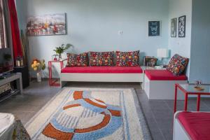 a living room with a red couch and a rug at ΑΝΑΚΑΙΝΙΣΜΕΝΗ ΜΟΝΟΚΑΤΟΙΚΙΑ 125 τμ ΣΤΟ ΚΕΝΤΡΟ ΜΕ ΚΗΠΟ in Missolonghi