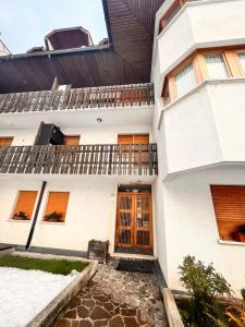 un edificio blanco con puertas y ventanas de madera en Stella Alpina, en Tarvisio