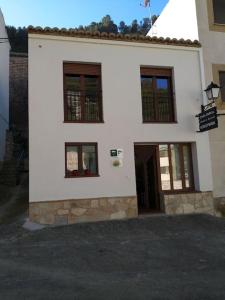 a white building with windows and a door at Casa rural Abuelo Daniel in Alcalá del Júcar
