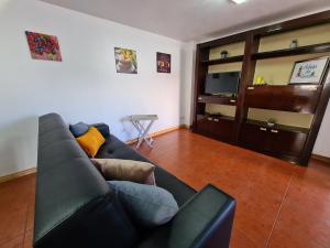 a living room with a black couch and a television at Adega do Costa in Prainha de Baixo