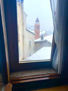 a window with a view of a building in the snow at Casa Belvedere Sant’Anna in Rivisondoli