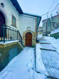 a building with a wooden door in the snow at Casa Belvedere Sant’Anna in Rivisondoli