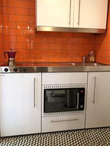a kitchen with white cabinets and a microwave at Beachfront apartment with wood burner & courtyard in St. Leonards