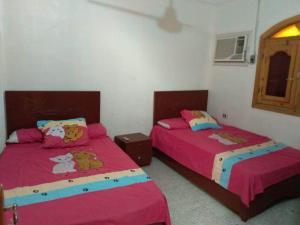 two beds in a bedroom with pink sheets at Zekry nubian guest house in Aswan