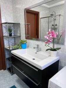 baño con lavabo, espejo y flores en Bnbook-Casa Andrea, en Cardano al Campo