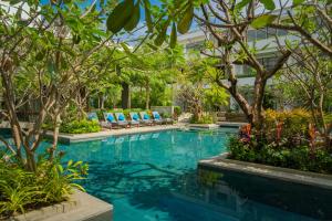 uma piscina com cadeiras azuis e árvores em Eightfold Urban Resort em Siem Reap