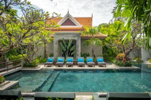 uma piscina em frente a uma villa com cadeiras azuis em Eightfold Urban Resort em Siem Reap