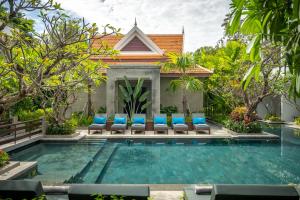a swimming pool in front of a villa with blue chairs at Eightfold Urban Resort in Siem Reap