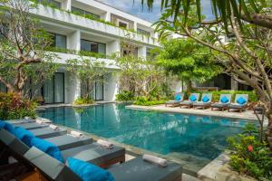 a hotel swimming pool with lounge chairs in front of a building at Eightfold Urban Resort in Siem Reap