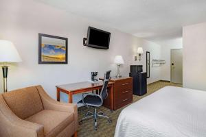 a hotel room with a bed and a desk and a chair at Days Inn by Wyndham Cambridge in Cambridge