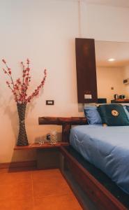 una camera da letto con un letto e un vaso con fiori su un tavolo di Passion Nai Harn a Nai Harn Beach