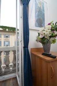 a vase of flowers on a table next to a window at Olympia Hotel in Genoa