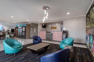 - un hall d'accueil avec des chaises bleues et un comptoir dans l'établissement Clarion Pointe Sulphur - Lake Charles, à Sulphur