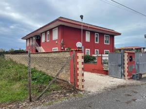 a red house with a fence in front of it at CASA ORCHIDEA in Fiumicino