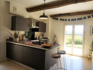 a kitchen with black cabinets and a counter with stools at Spacious holiday home in Bagnols en For t with pool in Bagnols-en-Forêt
