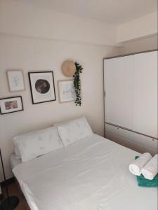 - un lit blanc dans une chambre avec des photos sur le mur dans l'établissement Celandine by DMCI - JM staycation, à Manille