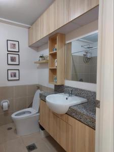 La salle de bains est pourvue de toilettes blanches et d'un lavabo. dans l'établissement Celandine by DMCI - JM staycation, à Manille