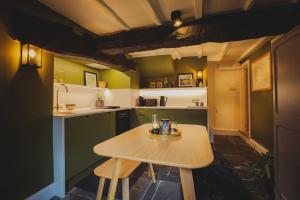una piccola cucina con tavolo in legno e armadi verdi di River Cottage, a luxurious and cosy riverside cottage for two a Welshpool