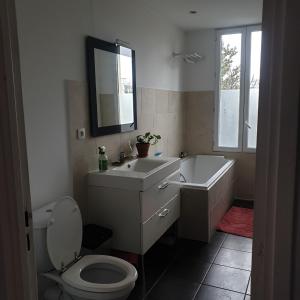a bathroom with a toilet and a sink and a tub at Klara's Guesthouse - Chambre chez L'habitant in Bagnolet