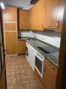 a kitchen with wooden cabinets and a white dishwasher at Casa Rural MAITETXU in Viscarret-Guerendiáin