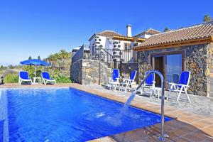 a swimming pool with blue chairs and a house at Casa Rural Pastor in Tijarafe