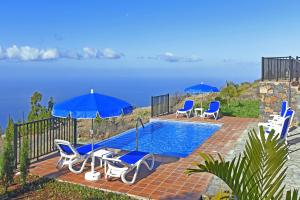 a swimming pool with chairs and umbrellas and the ocean at Casa Rural Pastor in Tijarafe