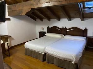 a bedroom with a large bed with white sheets at Casa Rural MAITETXU in Viscarret-Guerendiáin