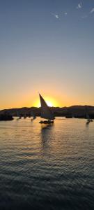 a sail boat in the water at sunset at Hamo Guest House in Aswan