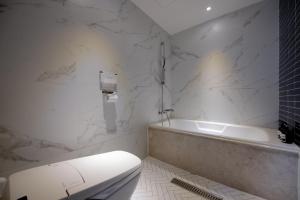 a white bathroom with a tub and a toilet at Hound Hotel Seomyeon-Beomcheon in Busan