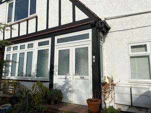 a white and black house with a white door at London Rooms with Free Parking 134 in Stone Grove