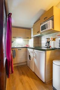 uma cozinha com uma máquina de lavar roupa e um micro-ondas em Grand studio tout confort pour 4 personnes em Brides-les-Bains