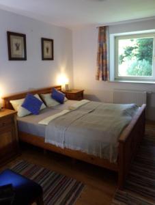 a bedroom with a bed with blue pillows and a window at Urlaubspension Die Mühle in Schöllnach