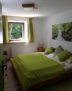 ein Schlafzimmer mit einem grünen Bett und einem Fenster in der Unterkunft Urlaubspension Die Mühle in Schöllnach
