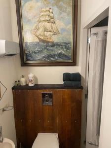 een badkamer met een toilet en een schilderij van een schip bij The Stables in Kampen