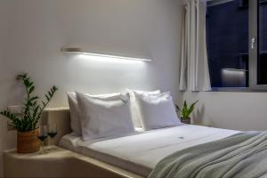 a bedroom with a bed with white pillows and a window at LOFUS Bio-Suites in Athens