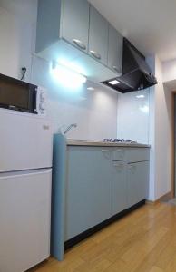 cocina con nevera blanca y fogones en 博多駅東貸切Hakataekihigashi Apartment LOFT付き高速WIFI 敷地内駐車場 地下鉄5分 国際線博多駅徒歩圏内 en Fukuoka