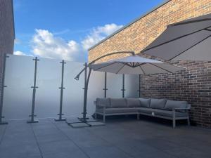 a couch sitting on a patio with an umbrella at Thats The Pad - 2 Bedroom pied-a-terre apartment in Wimbledon in London
