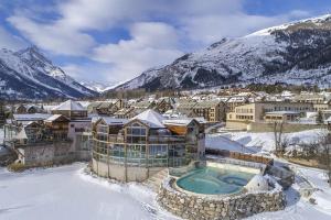 a resort with a swimming pool in the snow at Les Suites du Monetier, alliant le charme et l'authenticité d'un chalet de prestige au cœur du village in Le Monêtier-les-Bains