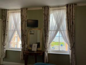 a room with two windows and a table and a mirror at The Captain's Lodge accommodation in Whitby