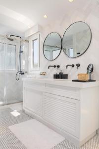 a white bathroom with a sink and a mirror at Seafront Luxury villa "Tesoro Mio" in Zakynthos Town