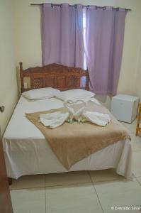 a bed with two white towels on it with a window at Pousada Canto Do Aconchego in Carrancas