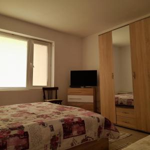 a bedroom with a bed and a flat screen tv at Къща за гости Лилия 