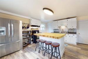 a kitchen with white cabinets and a island with bar stools at Written in the Stars in Penn Yan