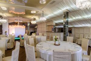a banquet room with white tables and chairs and chandeliers at Knyazhyi Dvir in Sokilʼnyky