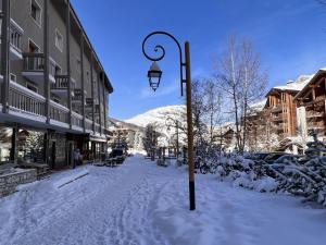 a snow covered street with a clock on a pole at Everest Hotel in Val-d'Isère