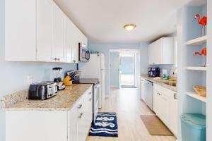 a kitchen with white cabinets and blue walls at First Street Retreat Lower in Mexico Beach